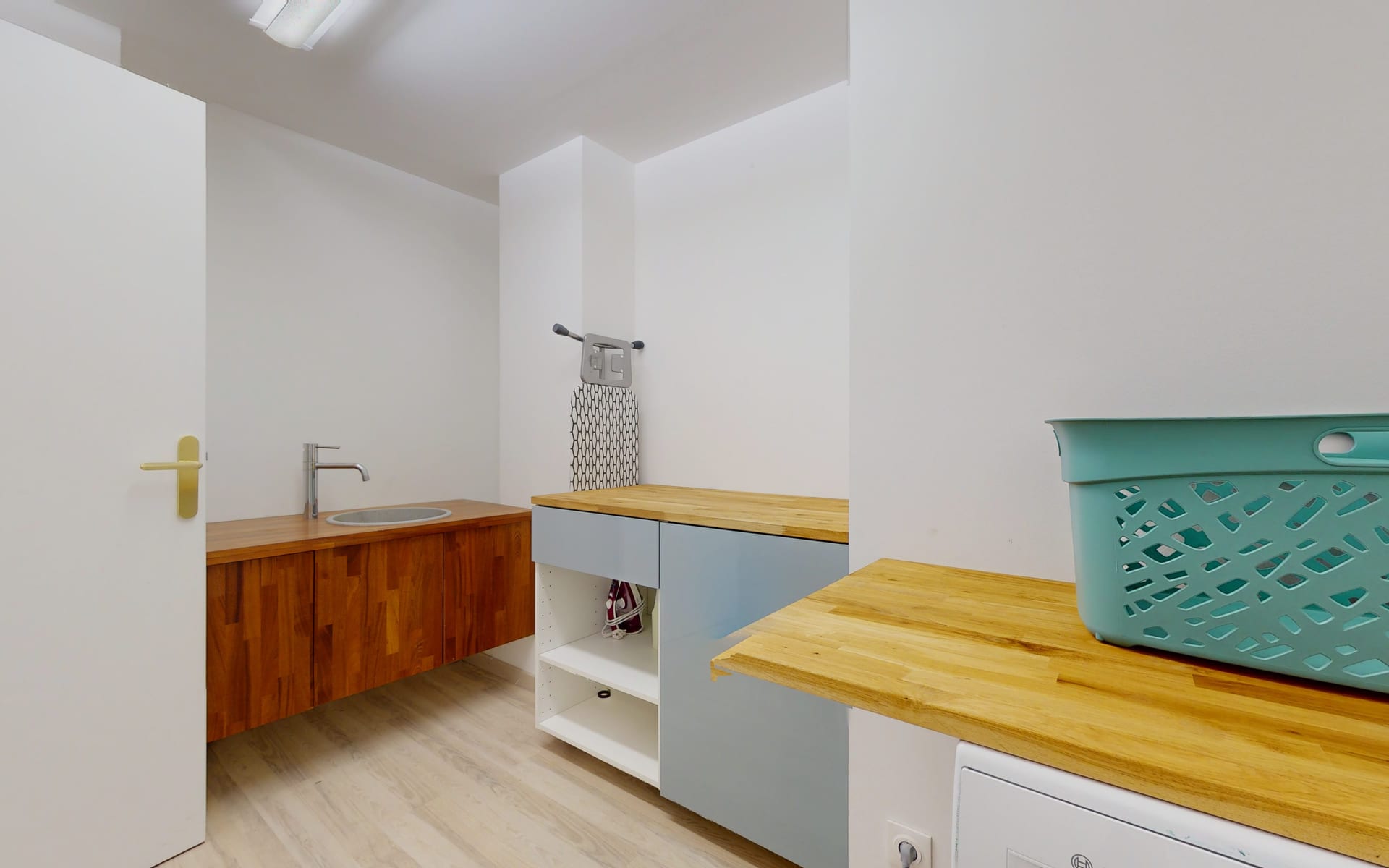 Buanderie avec évier, plan de travail en bois, lave-linge et table à repasser