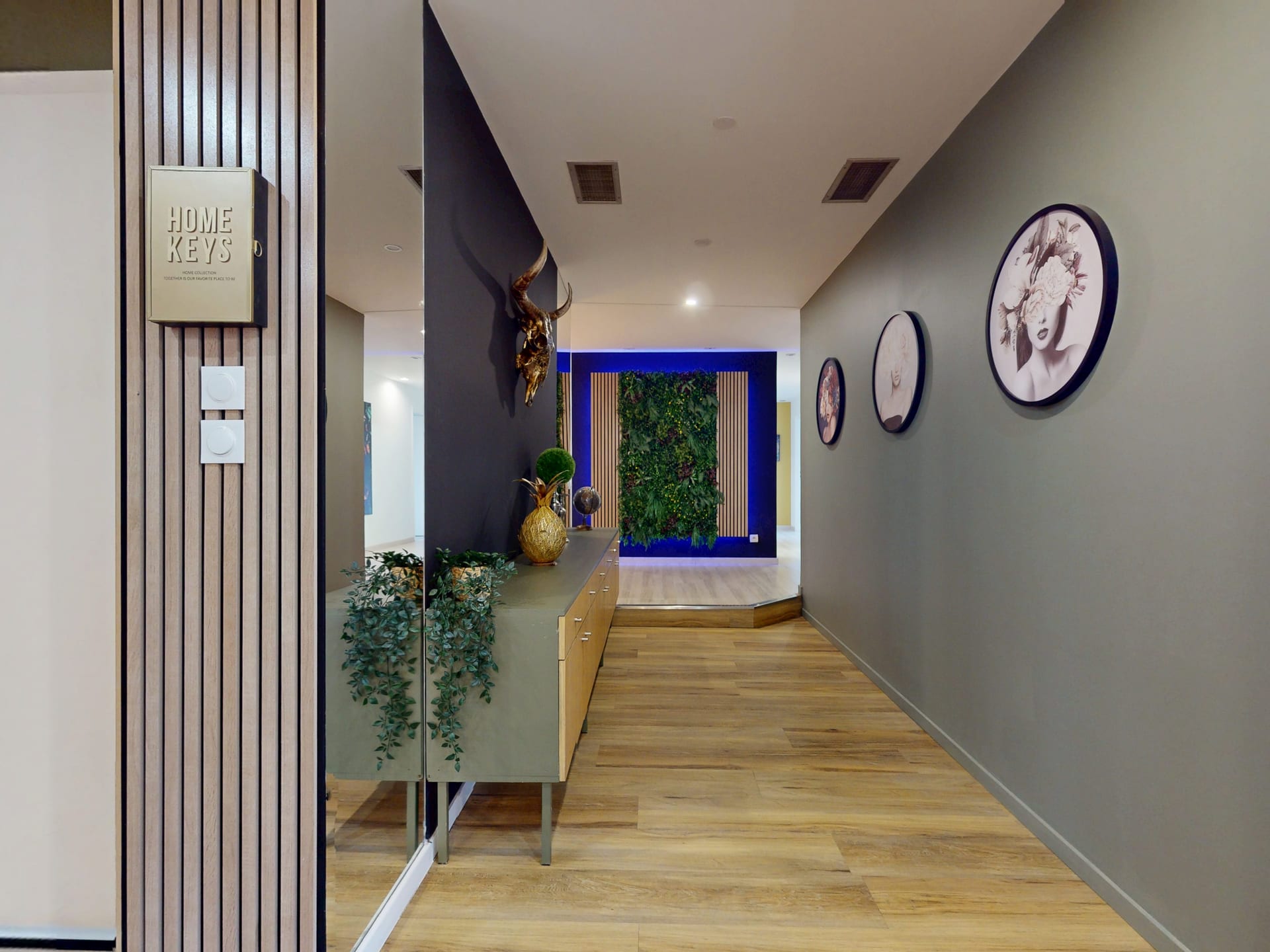 Entrée de l'appartement avec meuble d'appoint, miroir et mur végétal