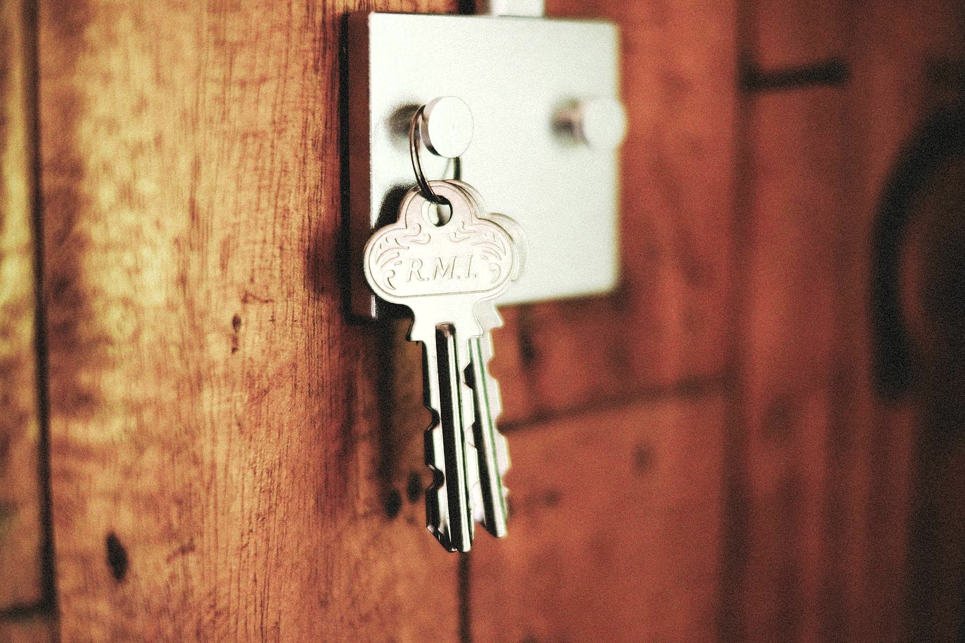 Trousseau de deux clés suspendu à un crochet sur une porte en bois